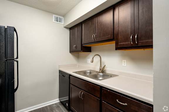 A kitchen with brown cabinets and a black refrigerator.
