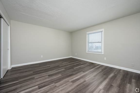A room with wooden flooring and a window with blinds.