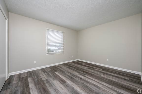 A room with wooden flooring and a window with blinds.