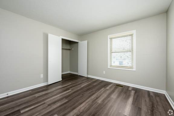 A room with a wooden floor and a window with blinds.