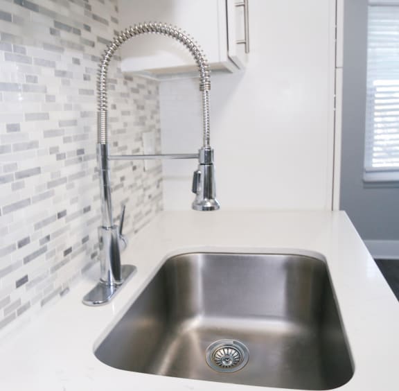 a kitchen sink with a faucet and a white counter top