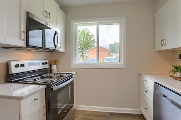 A kitchen with white cabinets and a black stove top oven.