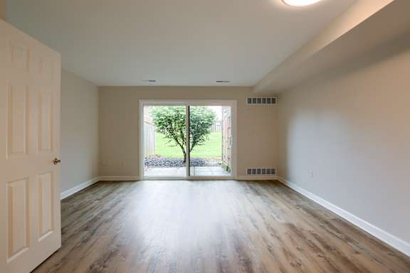 A room with a white door and a window with a tree outside.