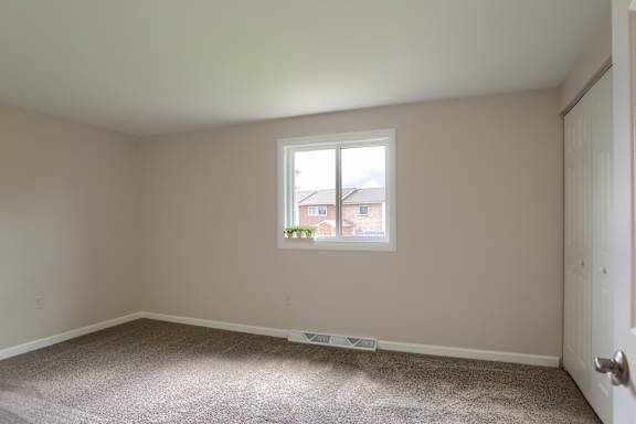 A room with a window and a carpeted floor.