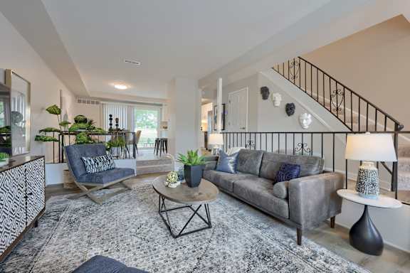 A living room with a grey couch, a black and white patterned rug, and a wooden coffee table.