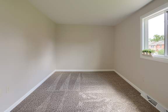 A room with a carpeted floor and a window.