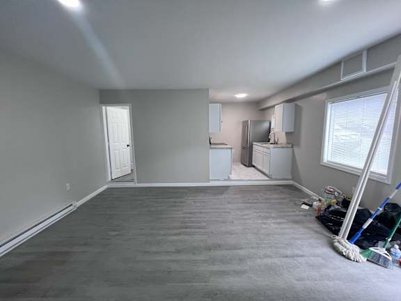 A room with a grey carpet and a window on the right side.