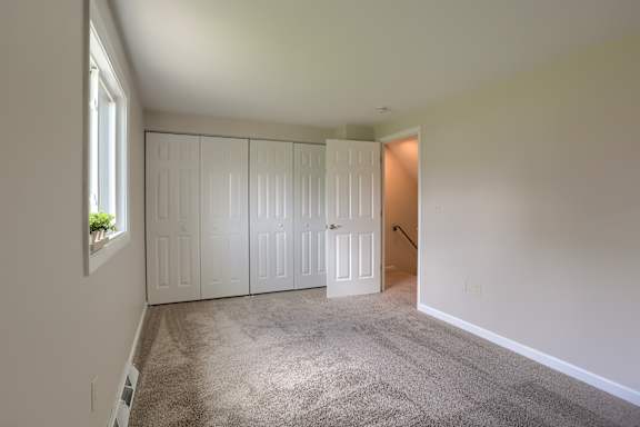 A room with white walls and a carpeted floor with a white door.