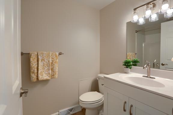 A bathroom with a toilet, sink, and mirror.