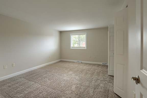 A room with a carpeted floor and a door on the right side.