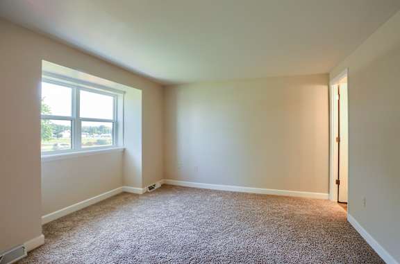 A room with a carpeted floor and a window.