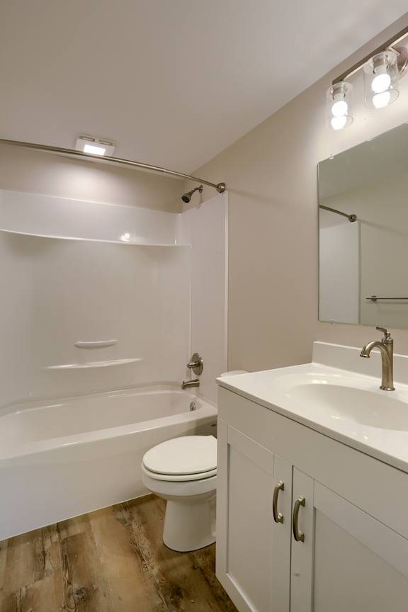 A white bathroom with a toilet, sink, and mirror.