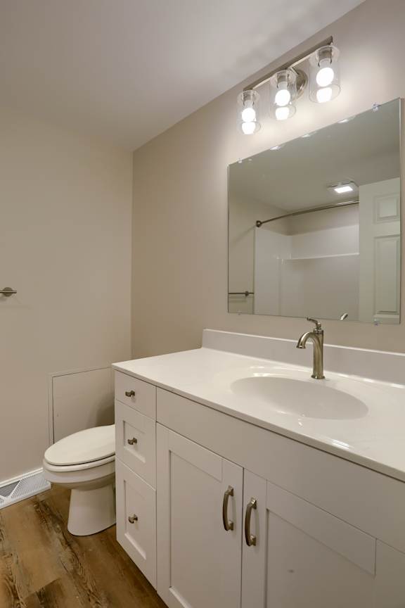 A white bathroom with a toilet, sink, and mirror.