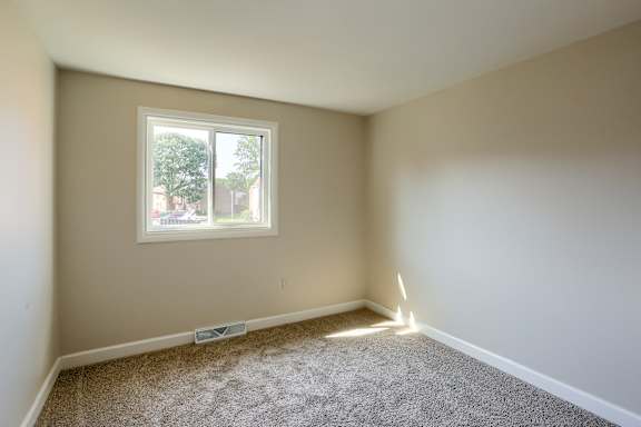 A room with a window and carpeted floor.