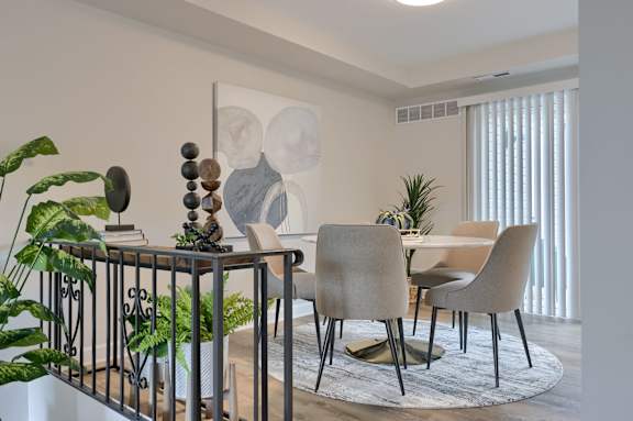A modern dining room with a table, chairs, and plants.