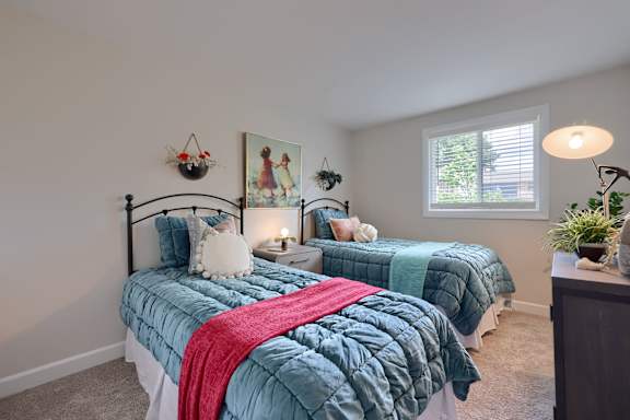 A bedroom with two beds and a painting on the wall.