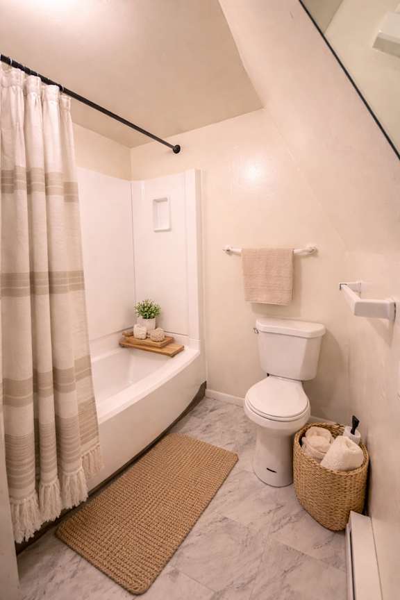 A white toilet sits next to a bathtub in a bathroom.