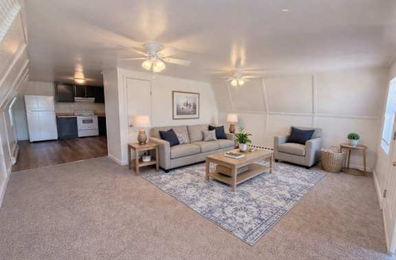 A living room with a rug, a couch, a coffee table, and a ceiling fan.