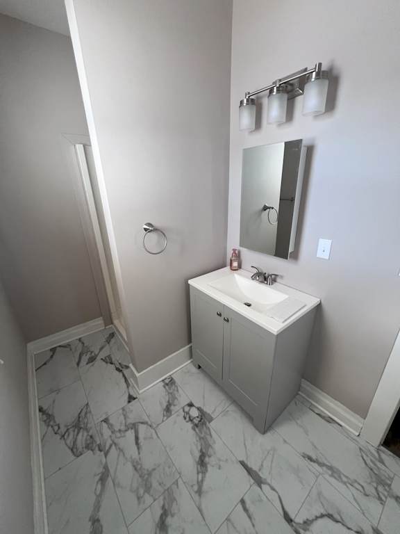 A bathroom with a marble floor and a white sink.