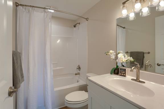 A white bathroom with a toilet, sink, and shower.
