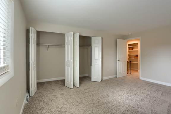 A room with a carpeted floor and a closet with white doors.