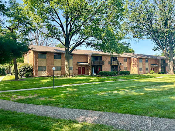 Apartment complex with green grass and trees.