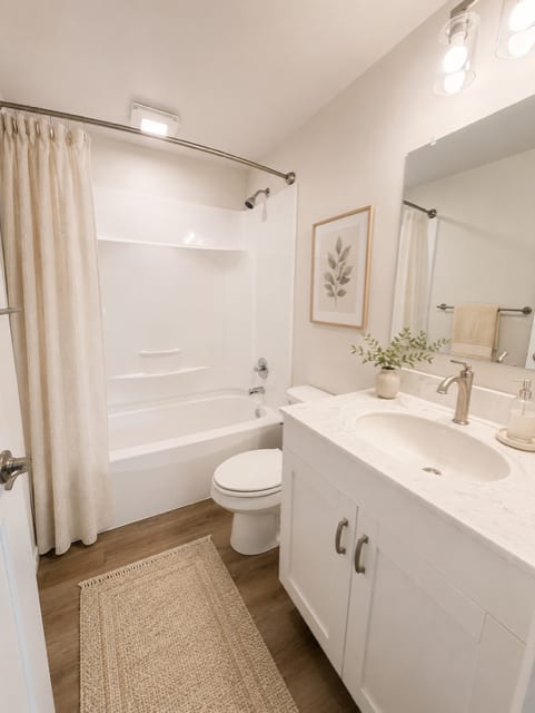 A white bathroom with a toilet, sink, and shower.