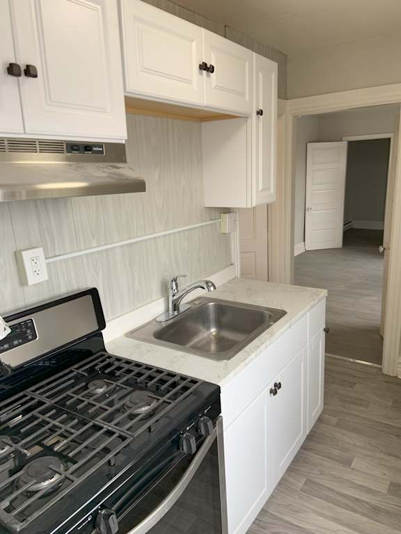 A kitchen with a stove, sink and cabinets.