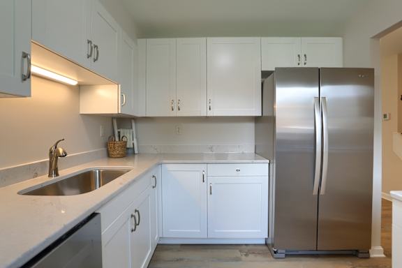 A kitchen with white cabinets and a stainless steel refrigerator.