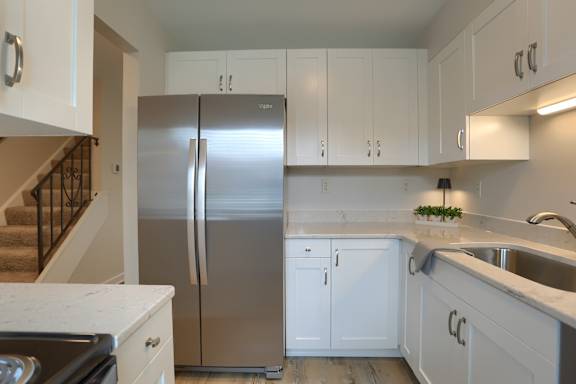 A kitchen with a stainless steel refrigerator and white cabinets.