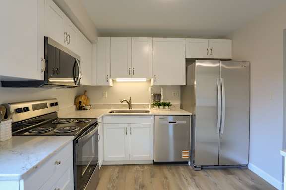 A kitchen with white cabinets and a stainless steel refrigerator.