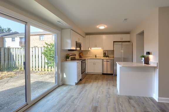 A modern kitchen with white cabinets and a wooden floor.
