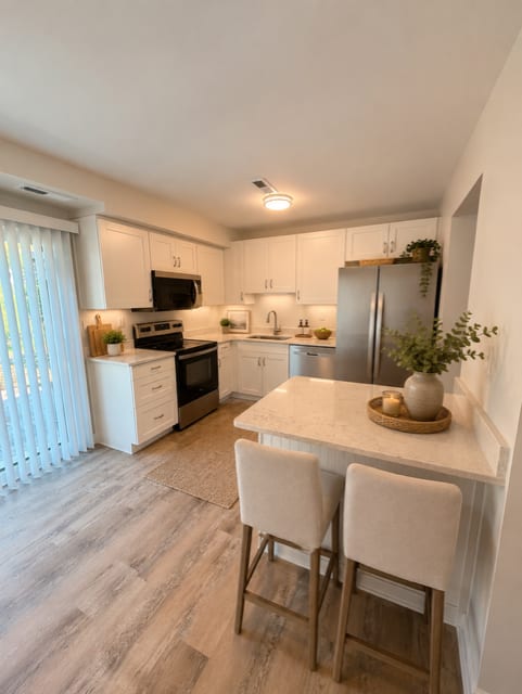 A kitchen with a white countertop and wooden chairs.