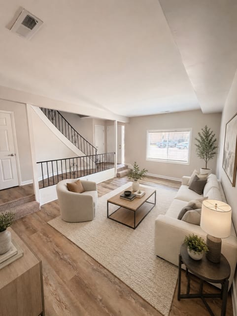 A living room with a white couch, a coffee table, and a staircase.