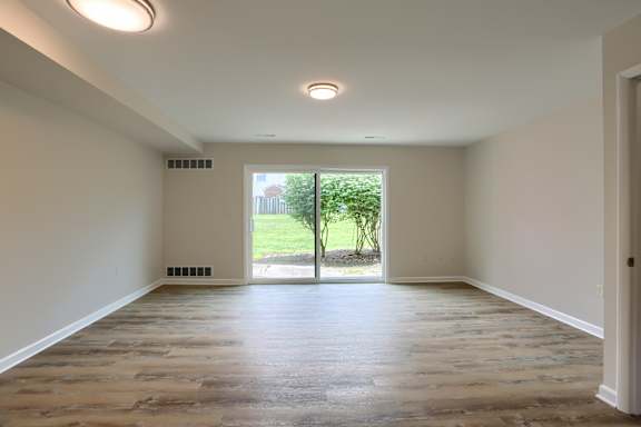 A room with wooden flooring and a window leading to a garden.