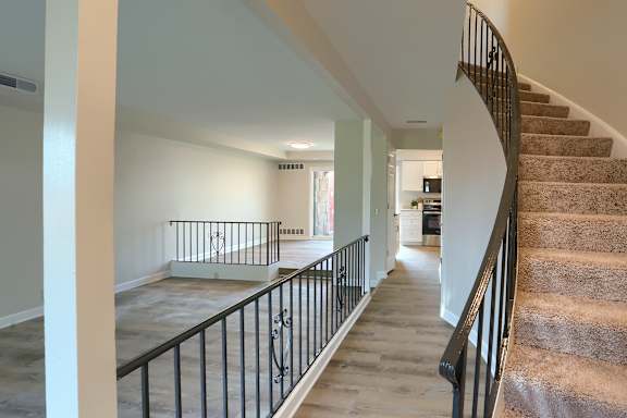A staircase with a black railing and beige carpeted steps.