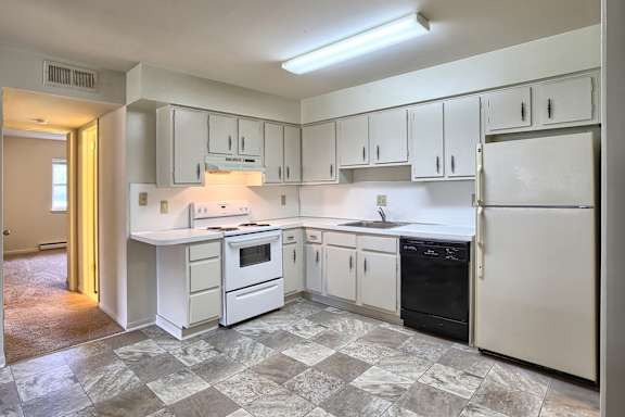 A kitchen with white appliances and cabinets.