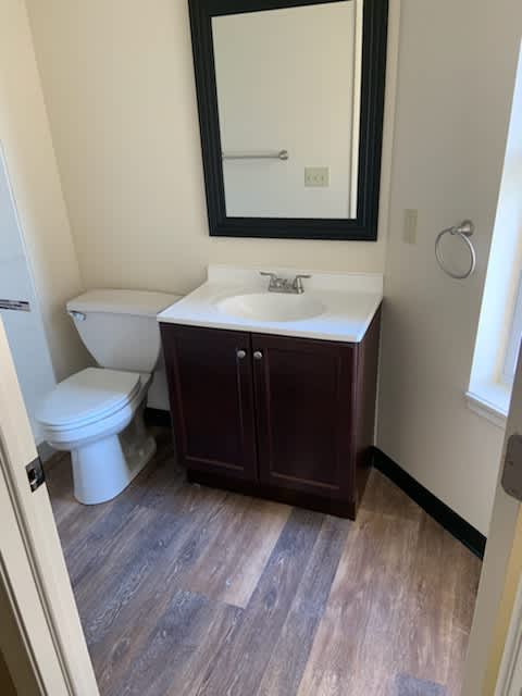 A bathroom with a toilet, sink, and mirror.