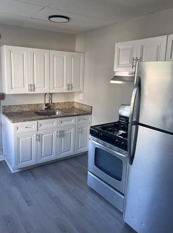A kitchen with white cabinets and a stainless steel refrigerator.