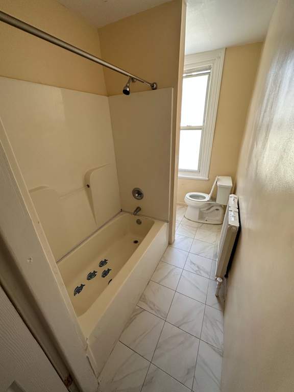 A bathroom with a toilet, tub, and window.