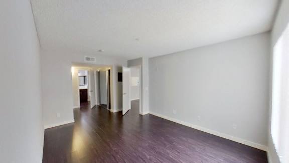 the living room and dining room of an apartment with wood floors and white walls