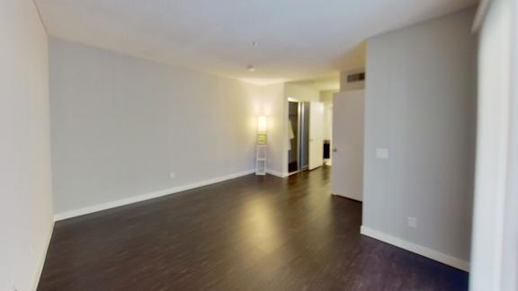 an empty living room with wood floors and white walls