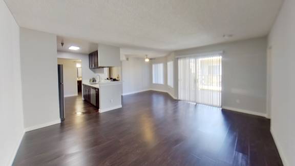 an empty living room and kitchen with wood flooring and a large window
