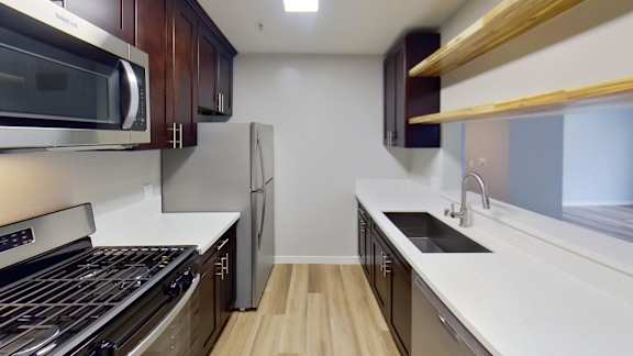 A modern kitchen with a stove, microwave, and refrigerator.