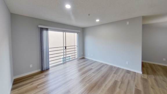 A room with wooden flooring and a sliding glass door.