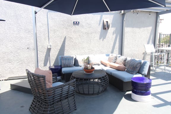 a patio with couches and chairs and an umbrella