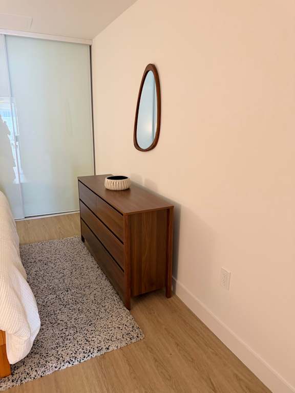 A wooden chest of drawers with a mirror above it.