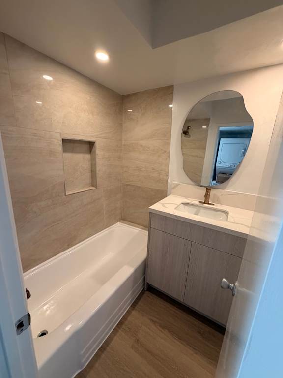 A bathroom with a tub, sink, and mirror.