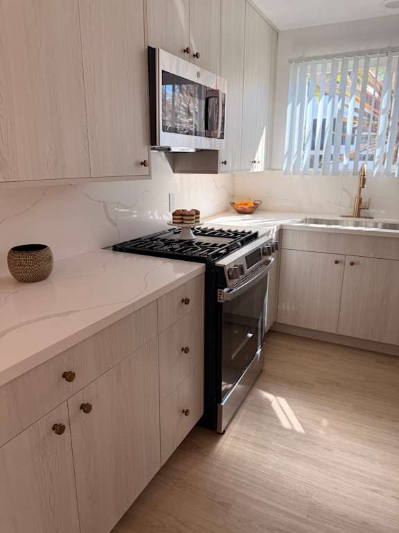 A modern kitchen with a stove top oven and a microwave above it.