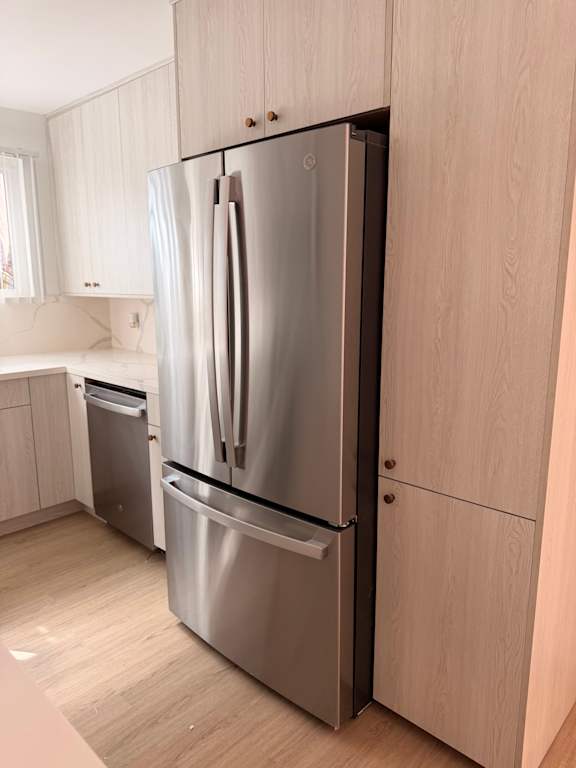 A stainless steel refrigerator with its door open in a kitchen.